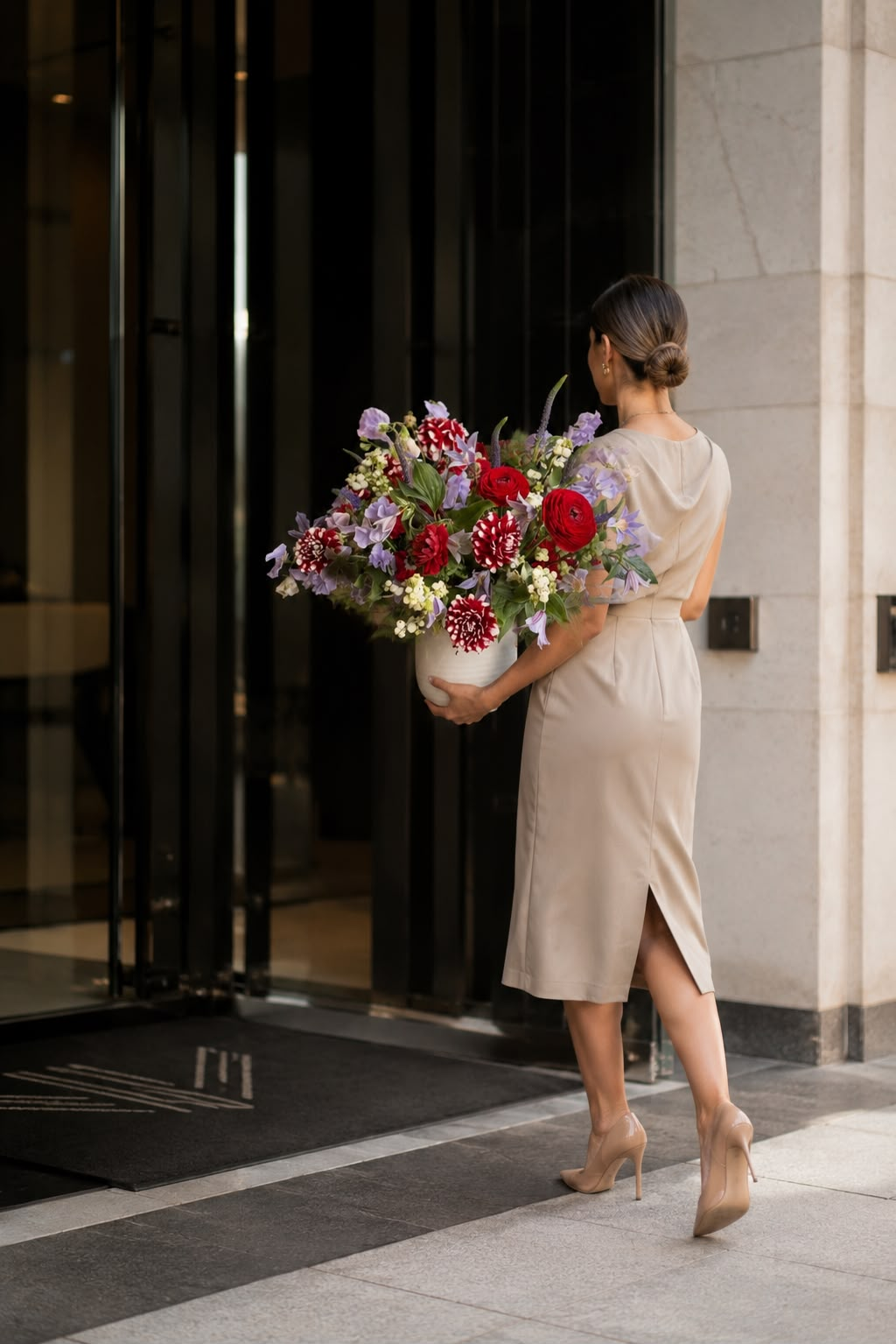 Elegant woman carrying a luxurious floral arrangement of red roses and seasonal blooms
